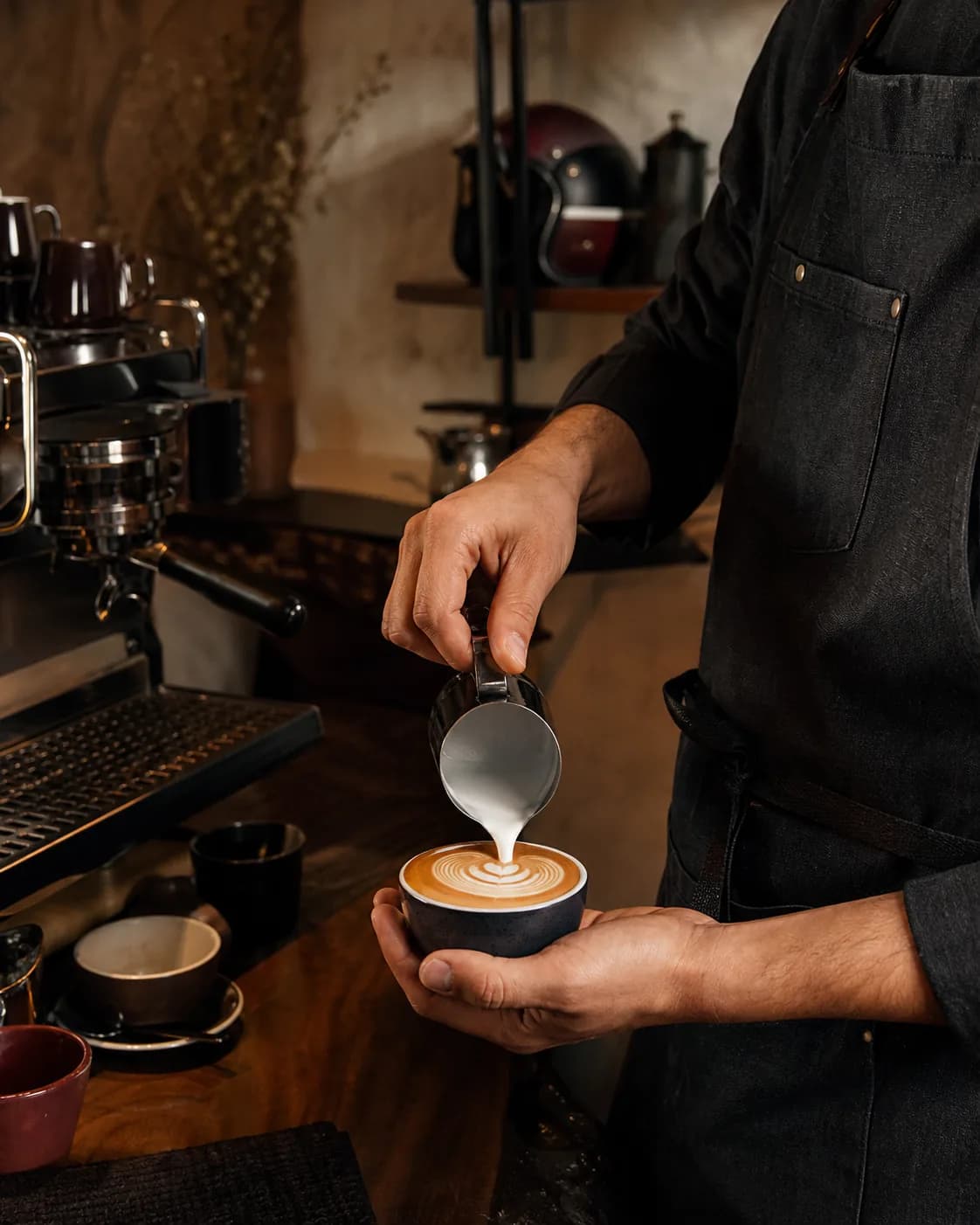 Barista pouring latte art behind the coffee bar
